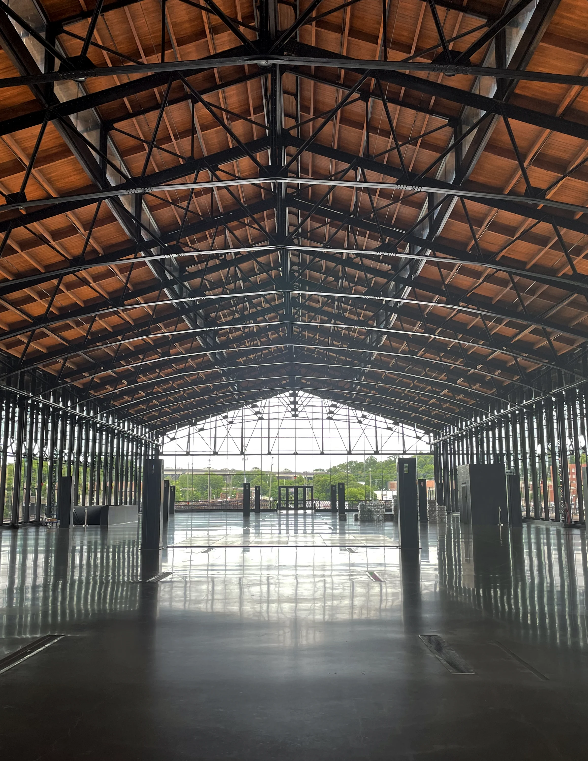 A large, empty train shed with visible beams in the ceiling opens to the outdoors