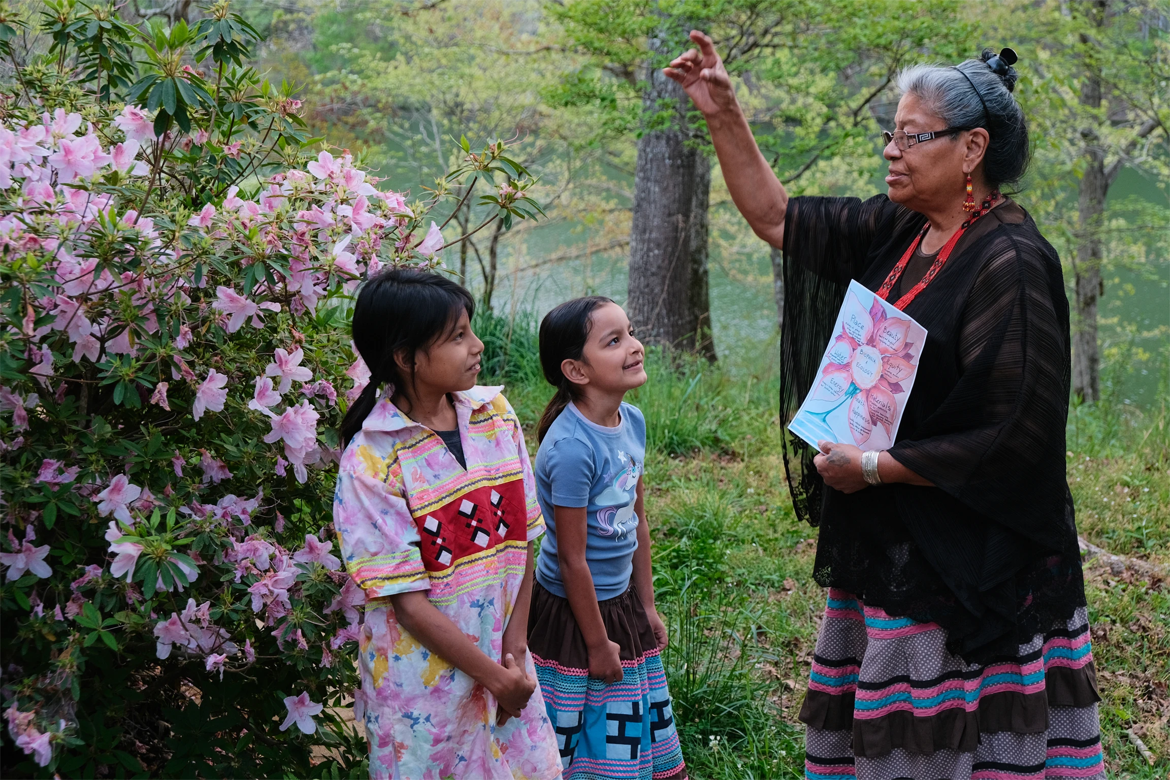 An indigenous Maskoke woman speaks to two young indigenous girls