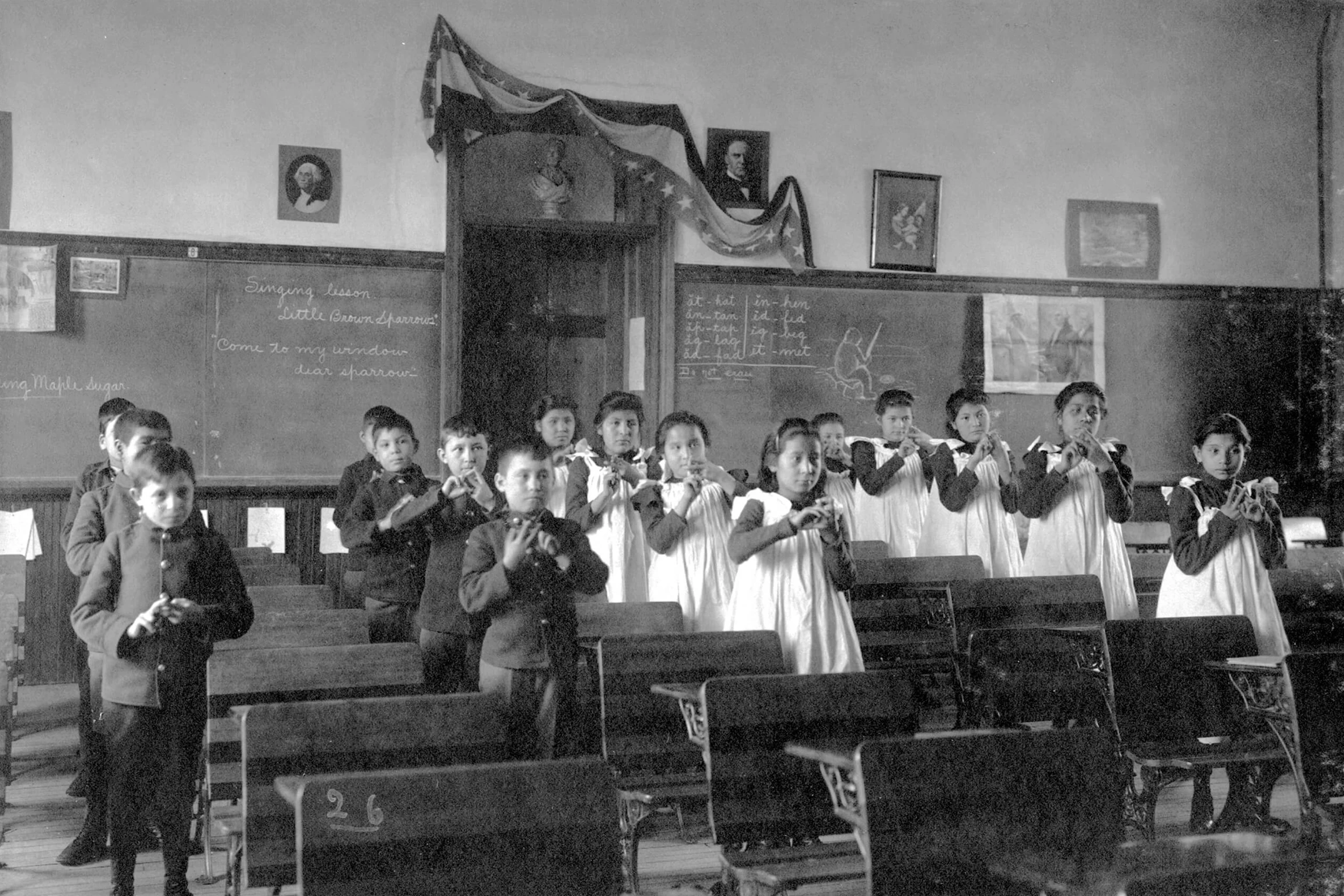 A group of young Native American school children dressed in uniforms in a classroom