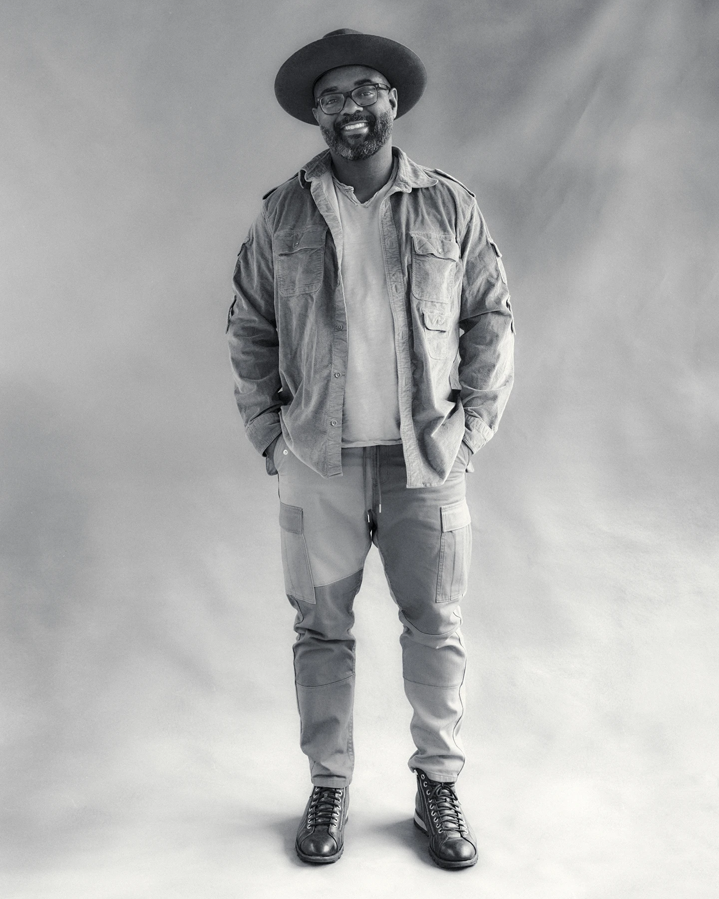 A Black author and lawyer stands facing the camera, and wearing a black hat.