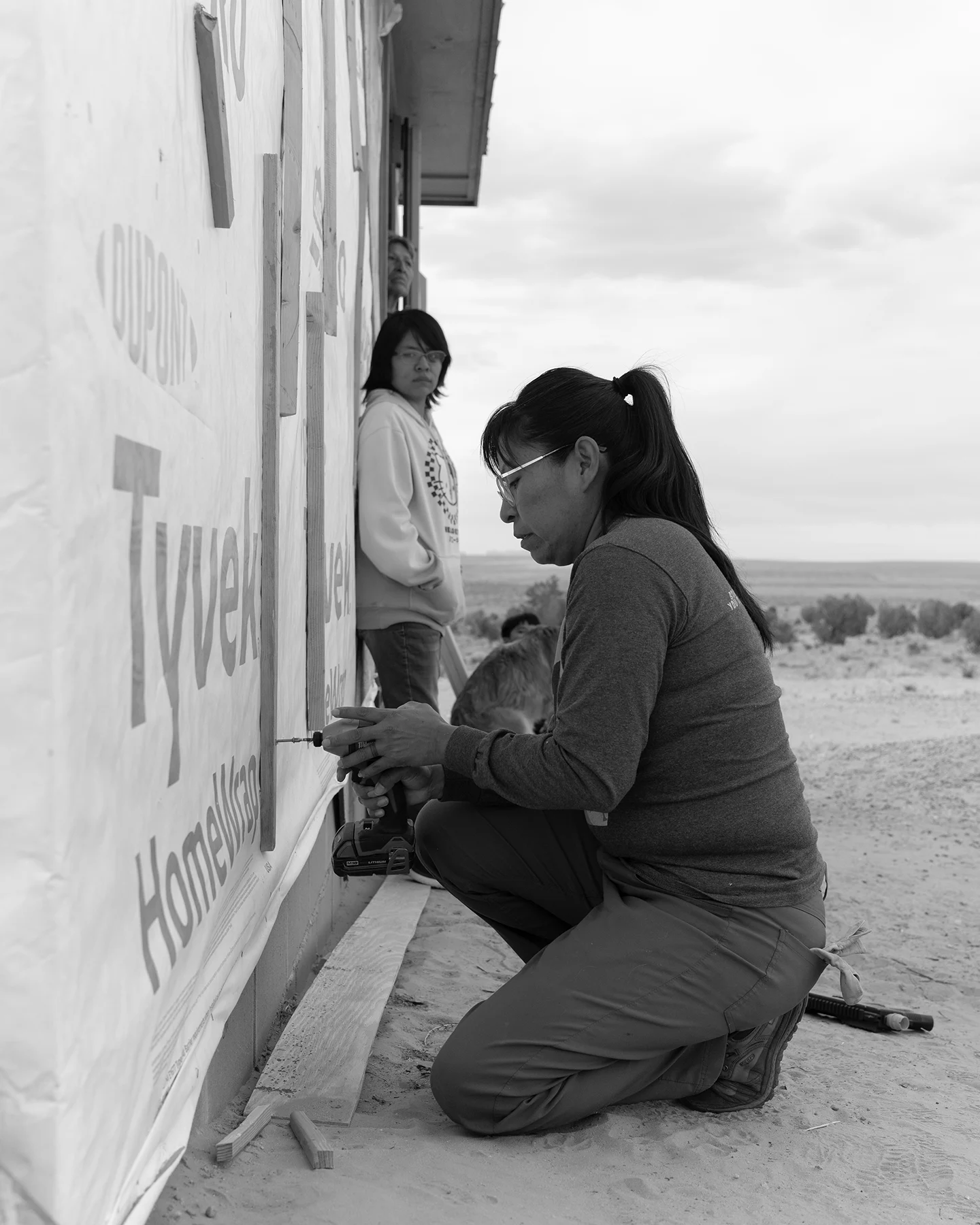 A young woman squats down while working on a house