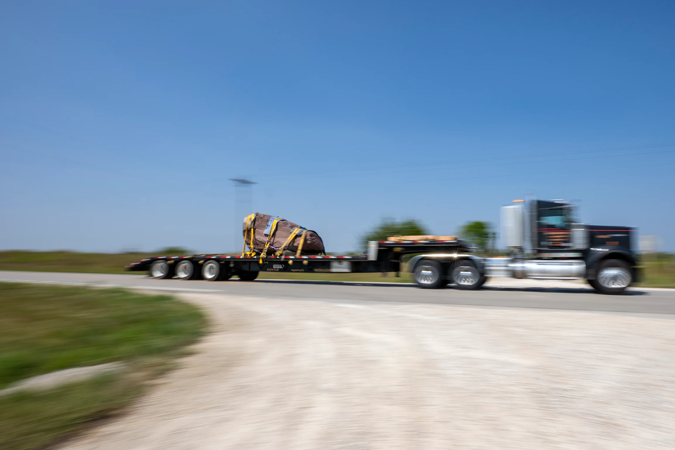 In motion, a sacred stone is tethered to a trailer that is hitched to a truck.