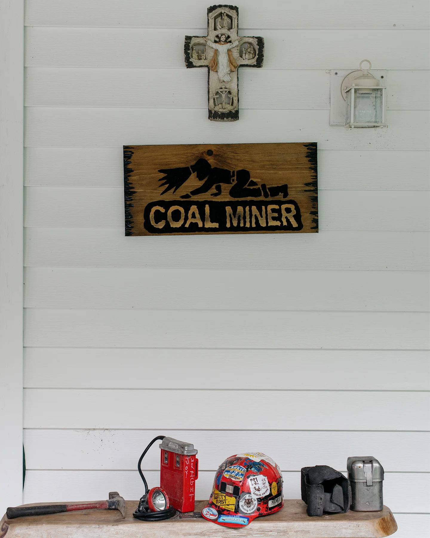 Display of coal mining memorabilia, including a miner’s helmet, headlamp, tools, and a wooden "Coal Miner" sign.