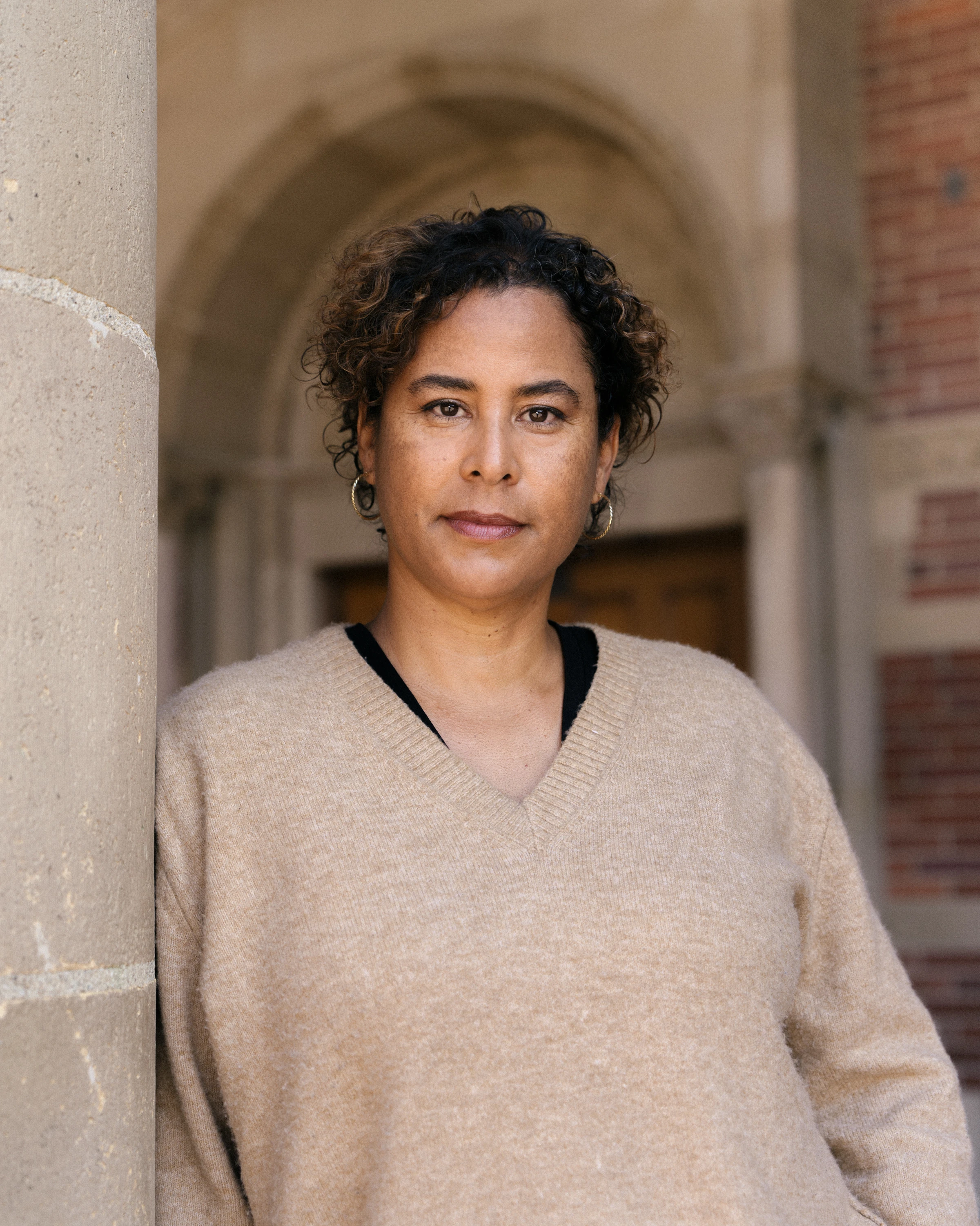 A historian stands in an archway and with a direct gaze at the camera.