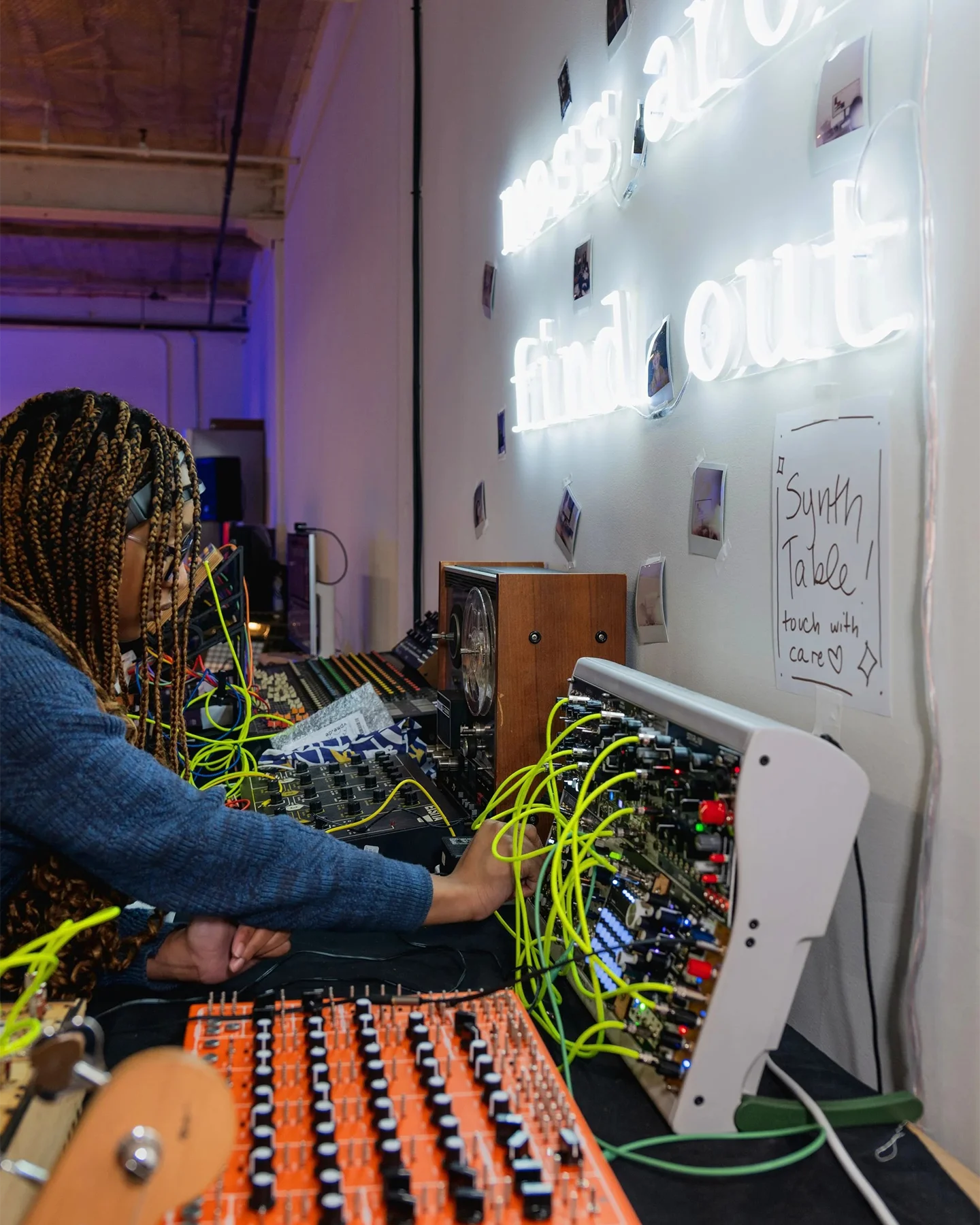 A student adjusts levels on a modular synthesizer with bright green patch cables
