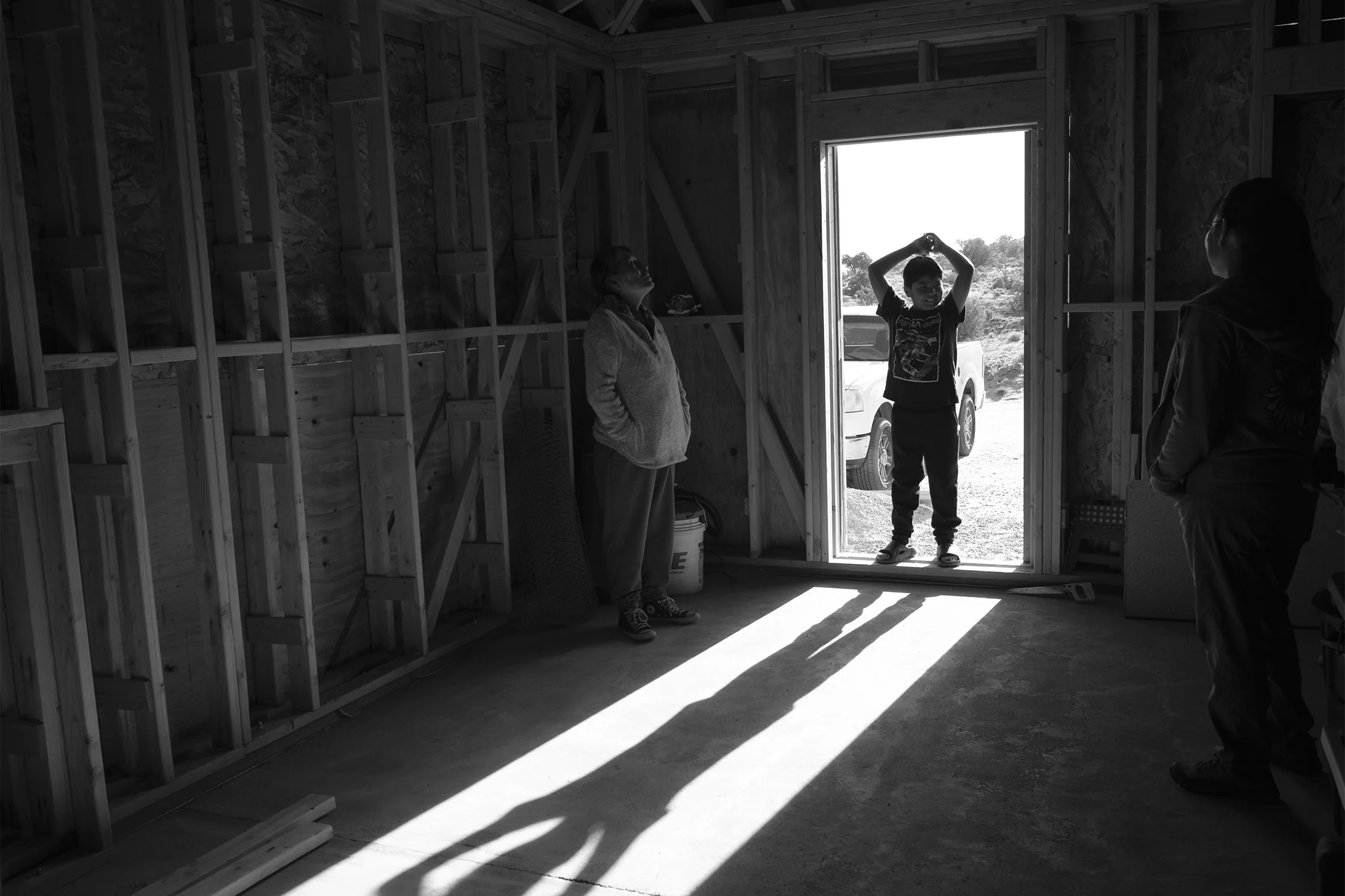 A young boy stands in a doorway of a building that is being framed