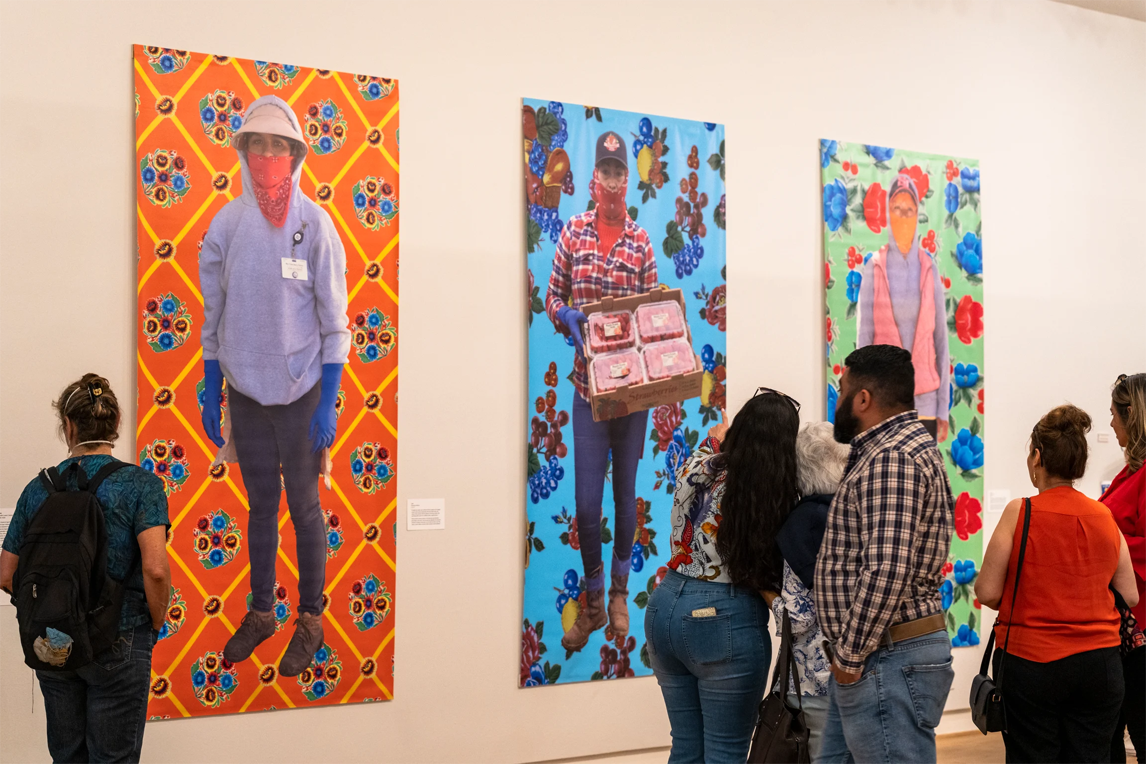 Gallery visitors mingle in an art space where large-scale artworks are displayed on the walls