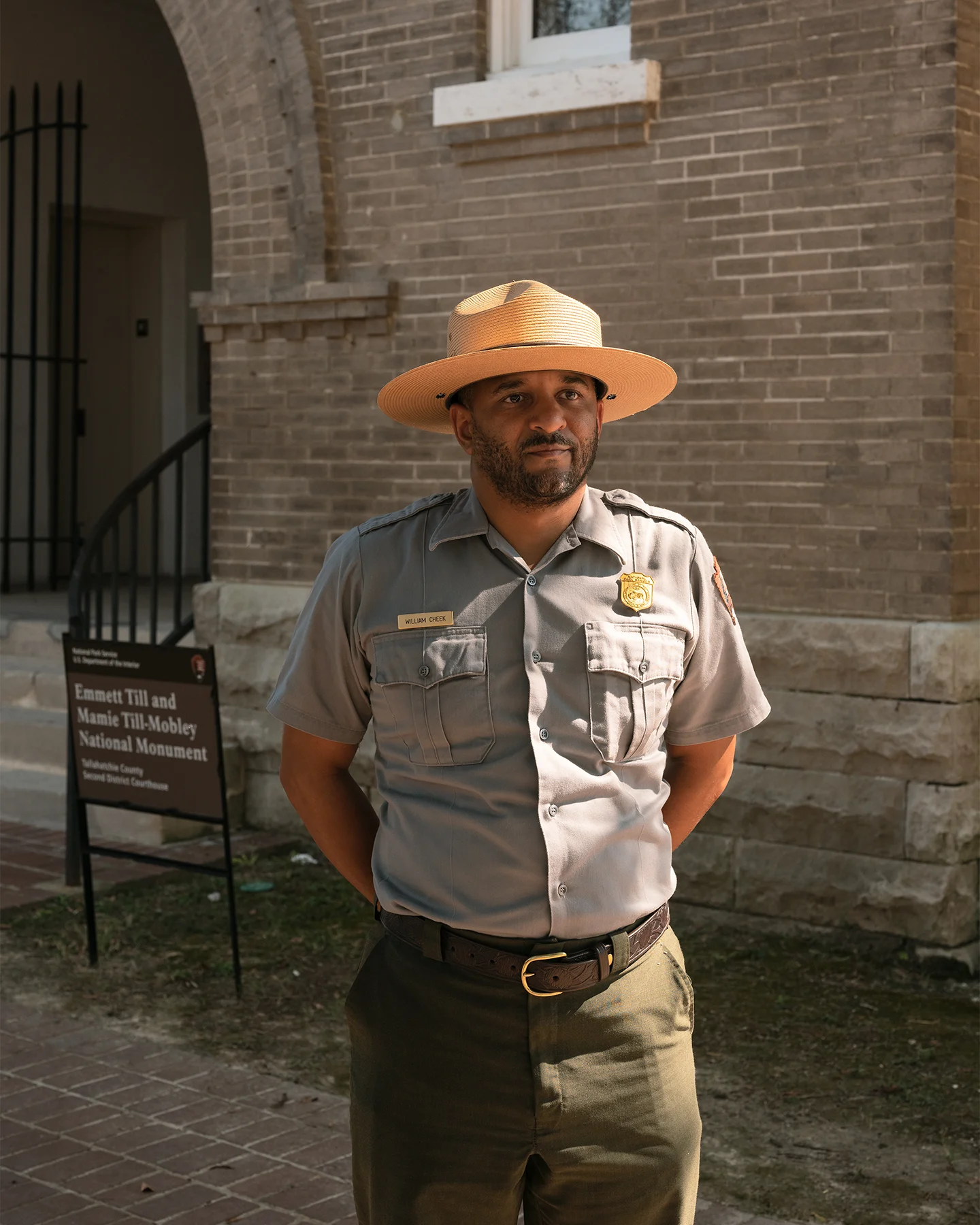 An African American man dressed in a state trooper uniform standing with his hands behind his back