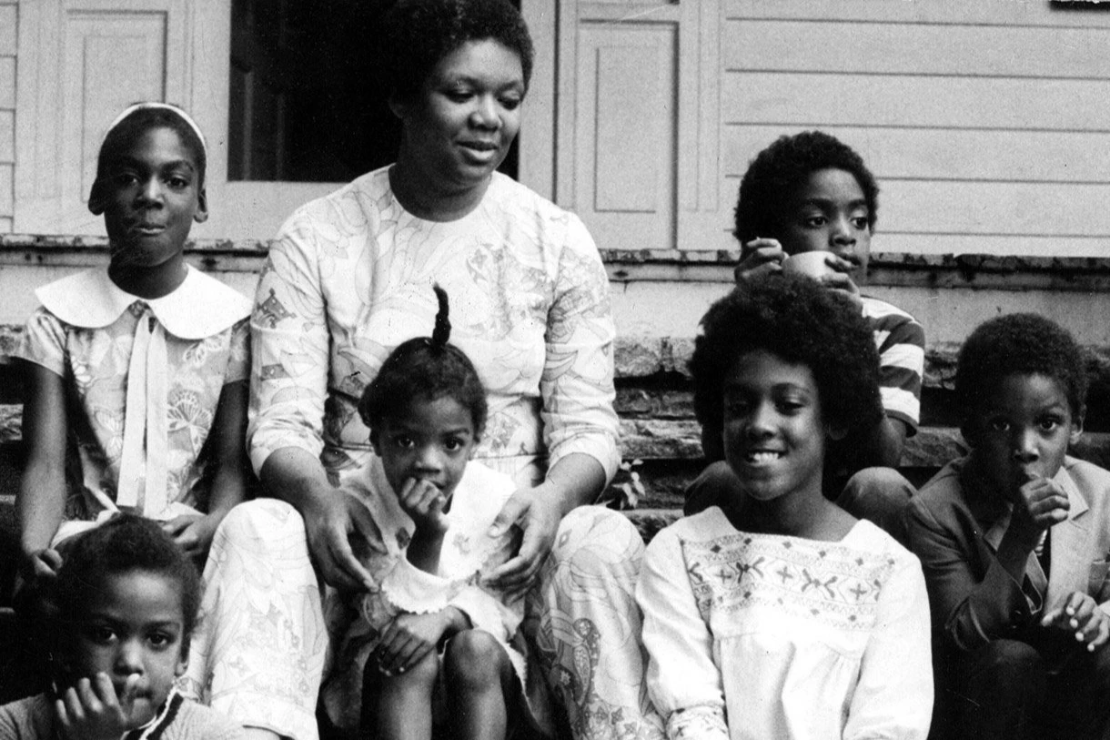 Six children sit with their mother on a porch