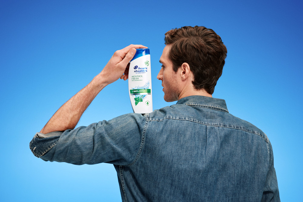 Hombre con champú Menthol Fresh sobre fondo azul, plano abierto