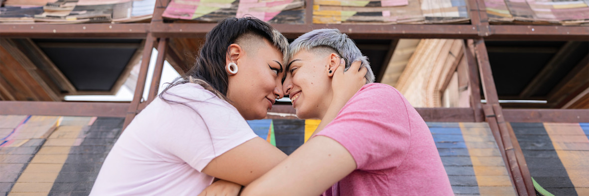 Una pareja se abraza estrechamente frente a un fondo vibrante y colorido.