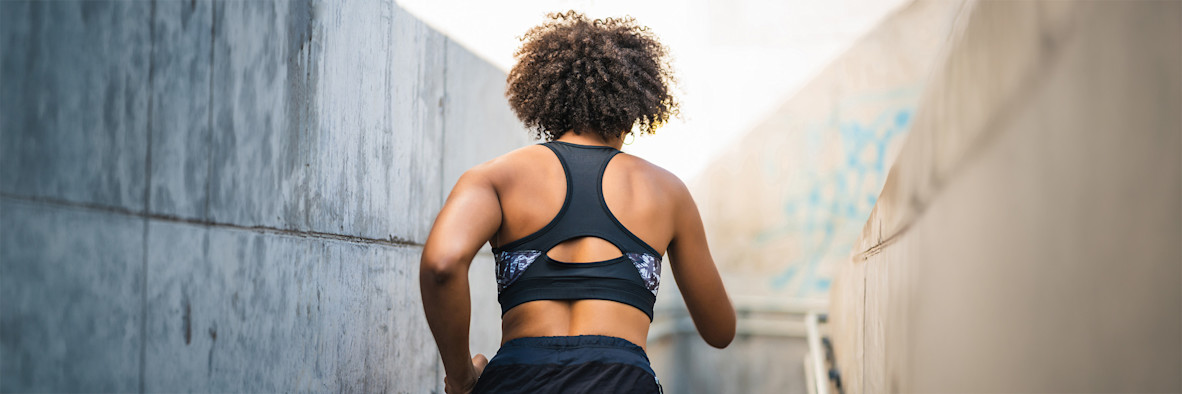 Una mujer con un sujetador deportivo y un peinado afro natural posa con confianza.