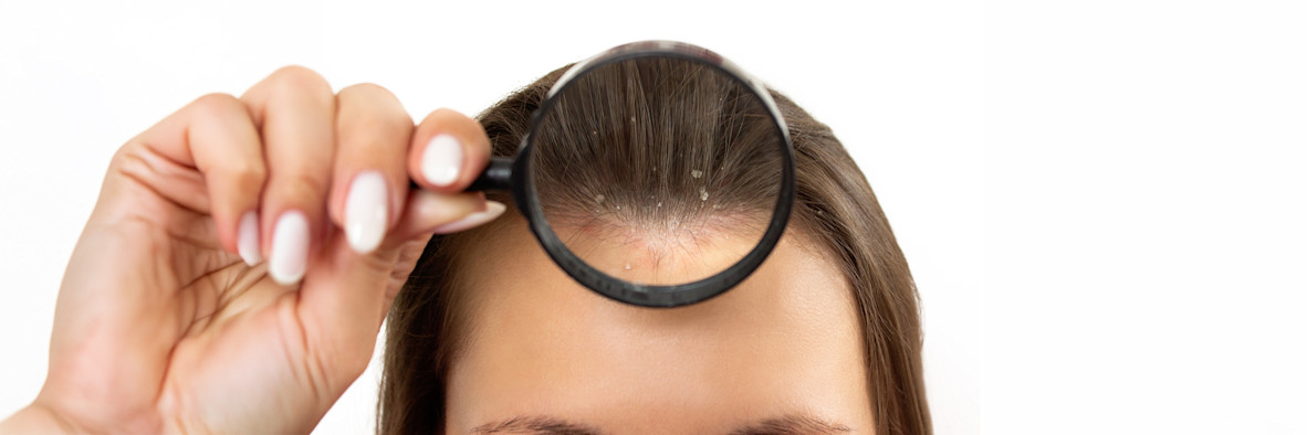 Una mujer sostiene su cabello y examina las puntas de cerca, buscando daños o puntas abiertas.