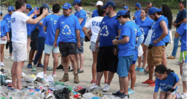Grupo de personas con camisetas azules reciclando basura