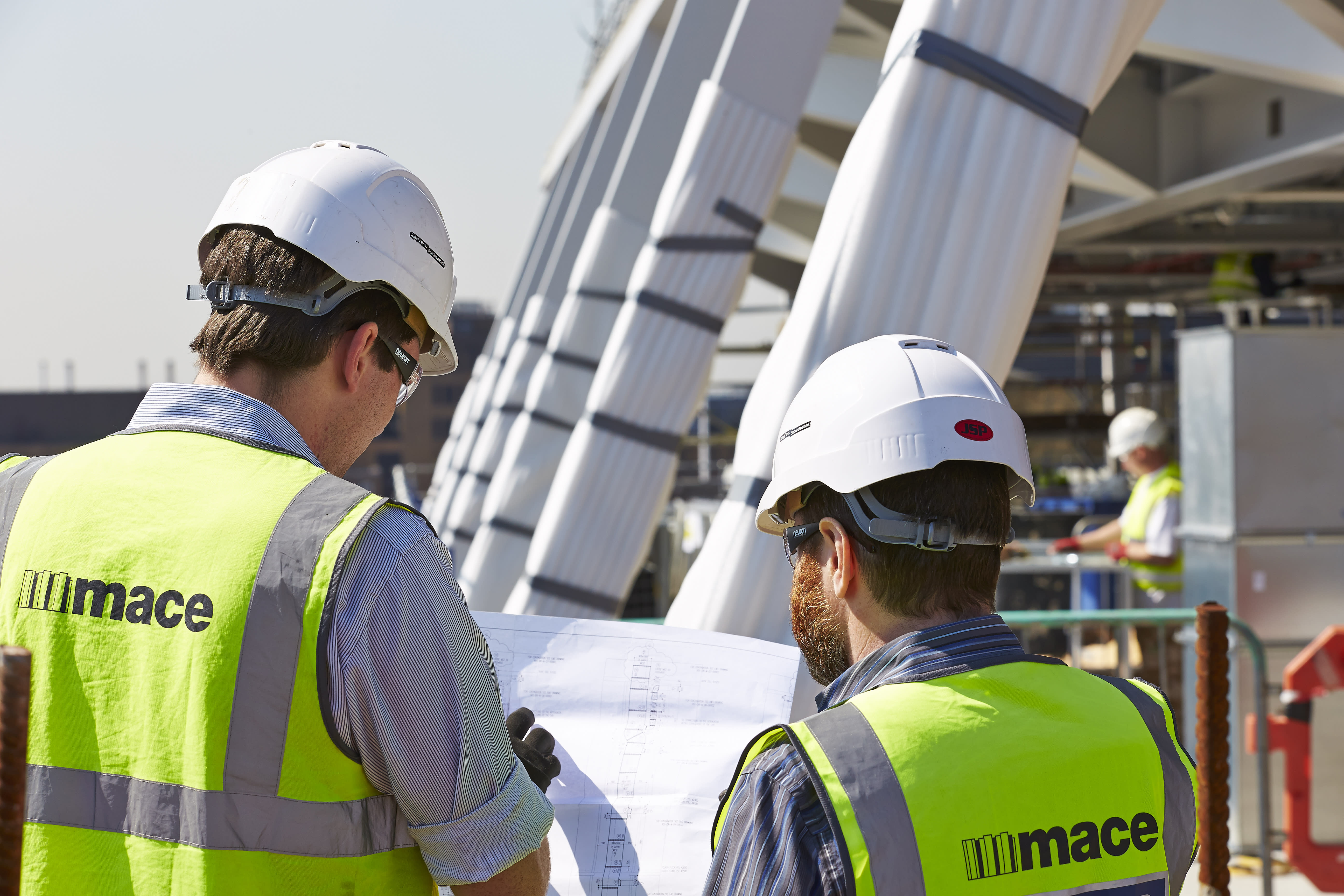 Two people in high vis jackets and hard hats looking at plans