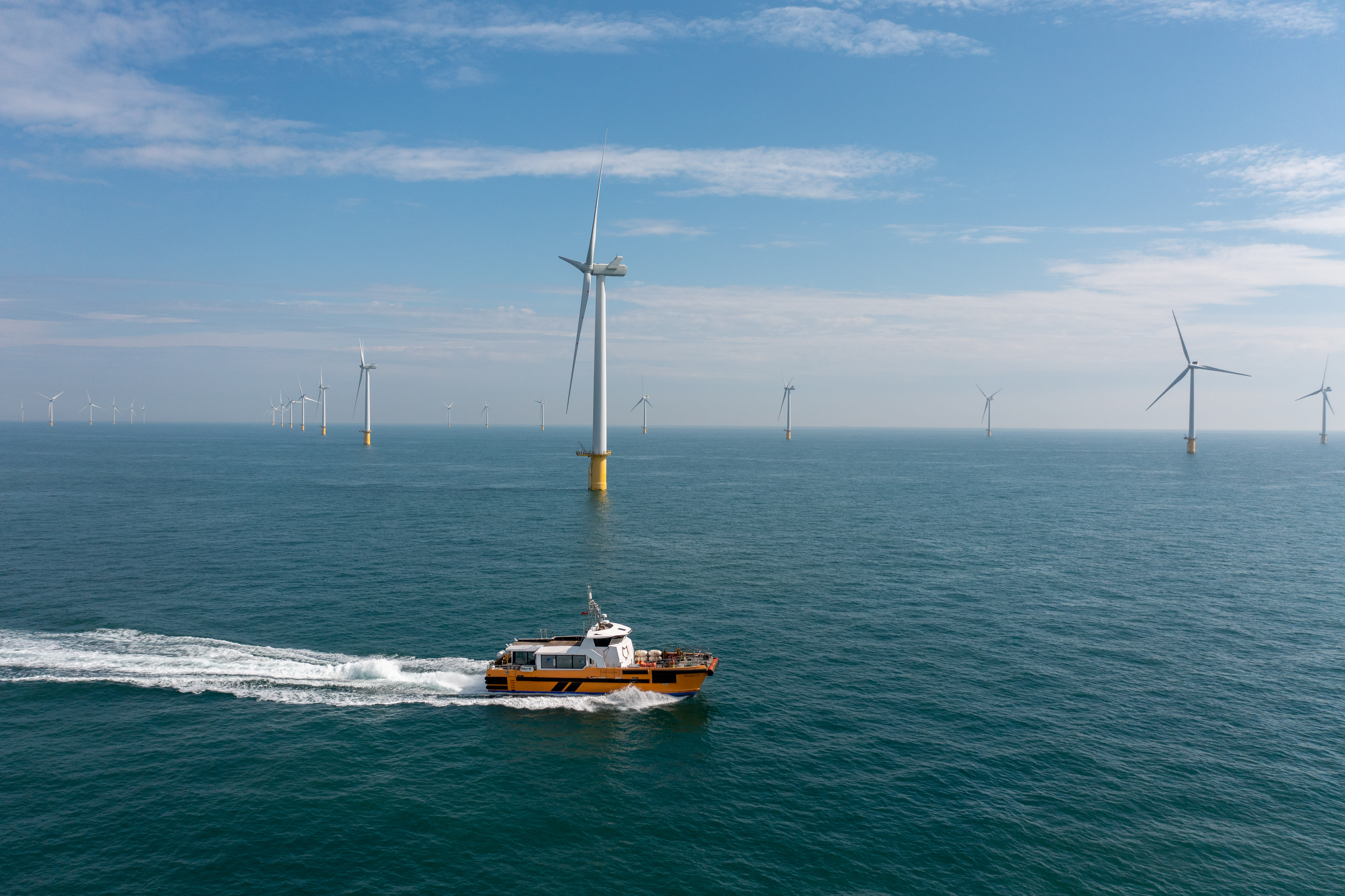 A boat moving in front of offshore wind turbines