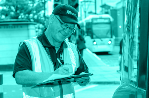 Transport for Greater Manchester worker with a clipboard stood on a bus