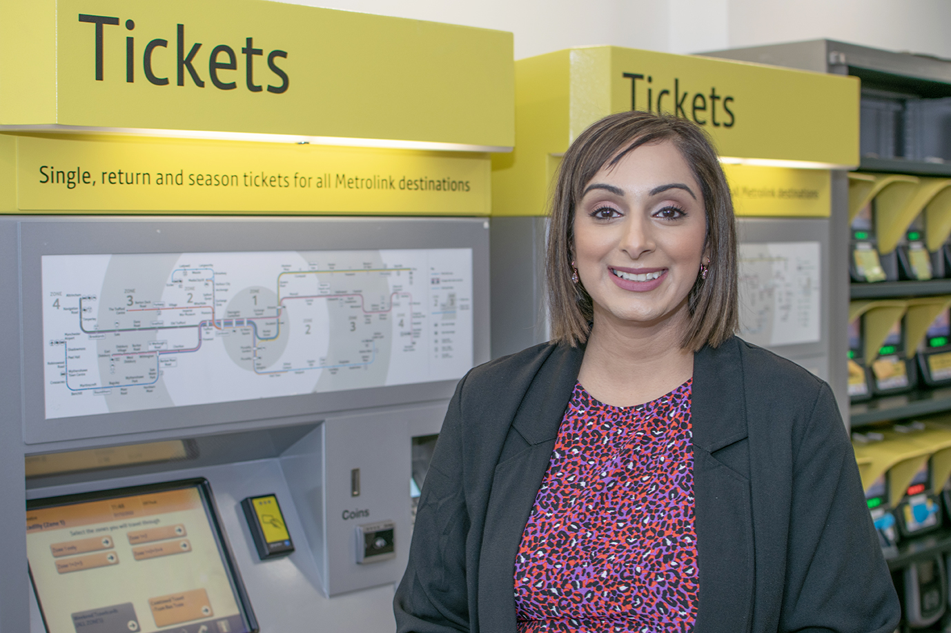 Picture of tfgm staff stood in front of a metrolink ticket machine