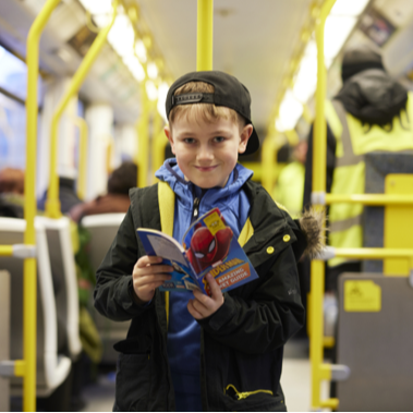 Young person on a tram in Manchester reading a book