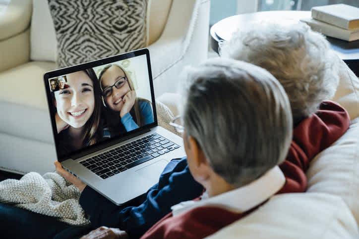 A retired couple sitting on a sofa and videoconferencing their grandkids on a laptop on Machine Readable Files