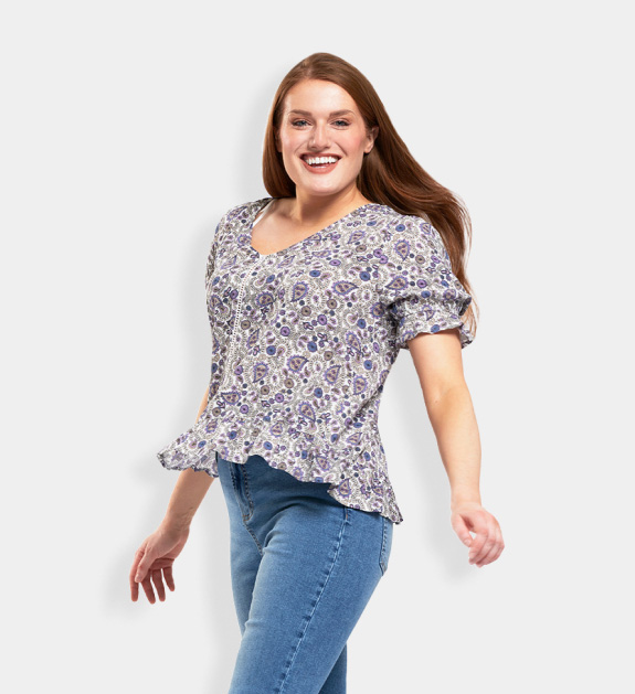 Women model wearing a floral blouse with a smocked waist and blue jeans.