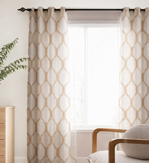Cream and tan hex pattern curtains displayed on a window in a living room. 