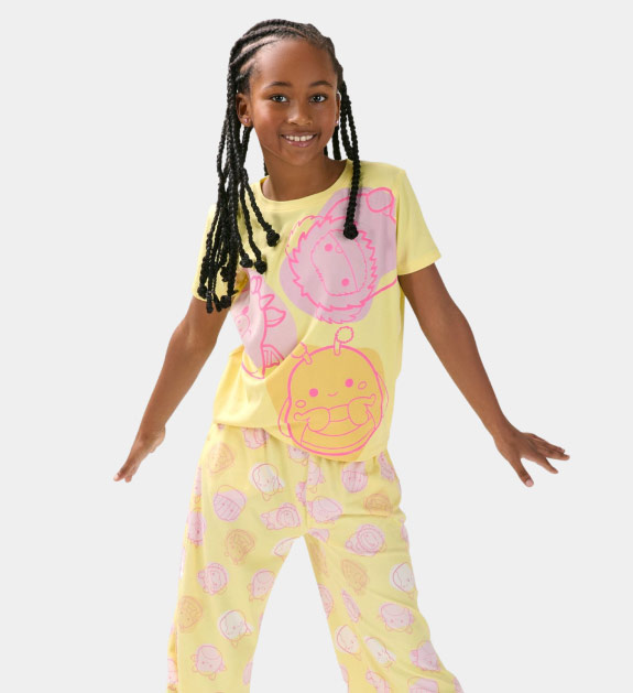 A girl wearing yellow Squishmallow print pyjamas. 