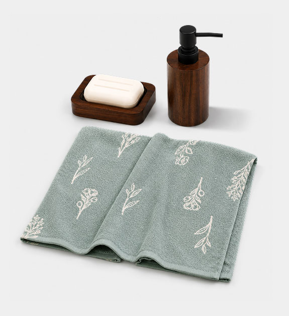 A brown soap dispenser and soap dish with teal hand towel. 
