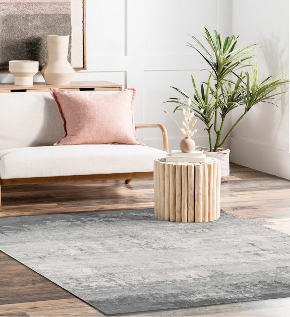 A 4 foot by 6 foot grey gradient rug displayed on a hardwood floor in a living room. 