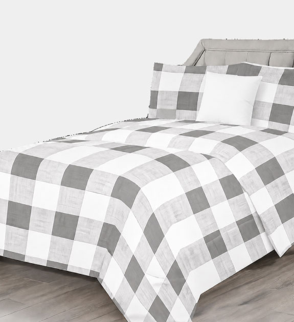 A white and grey plaid comforter set on a double bed. 
