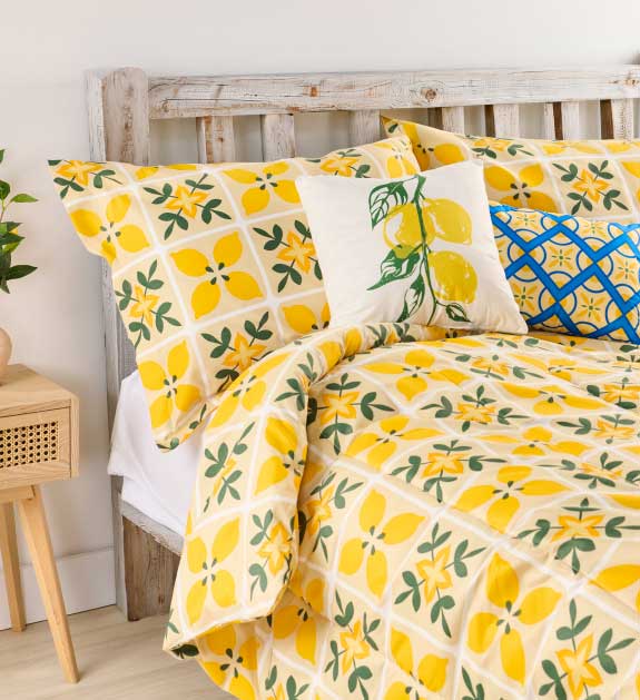A lemon yellow print bedding set displayed on a bed. 