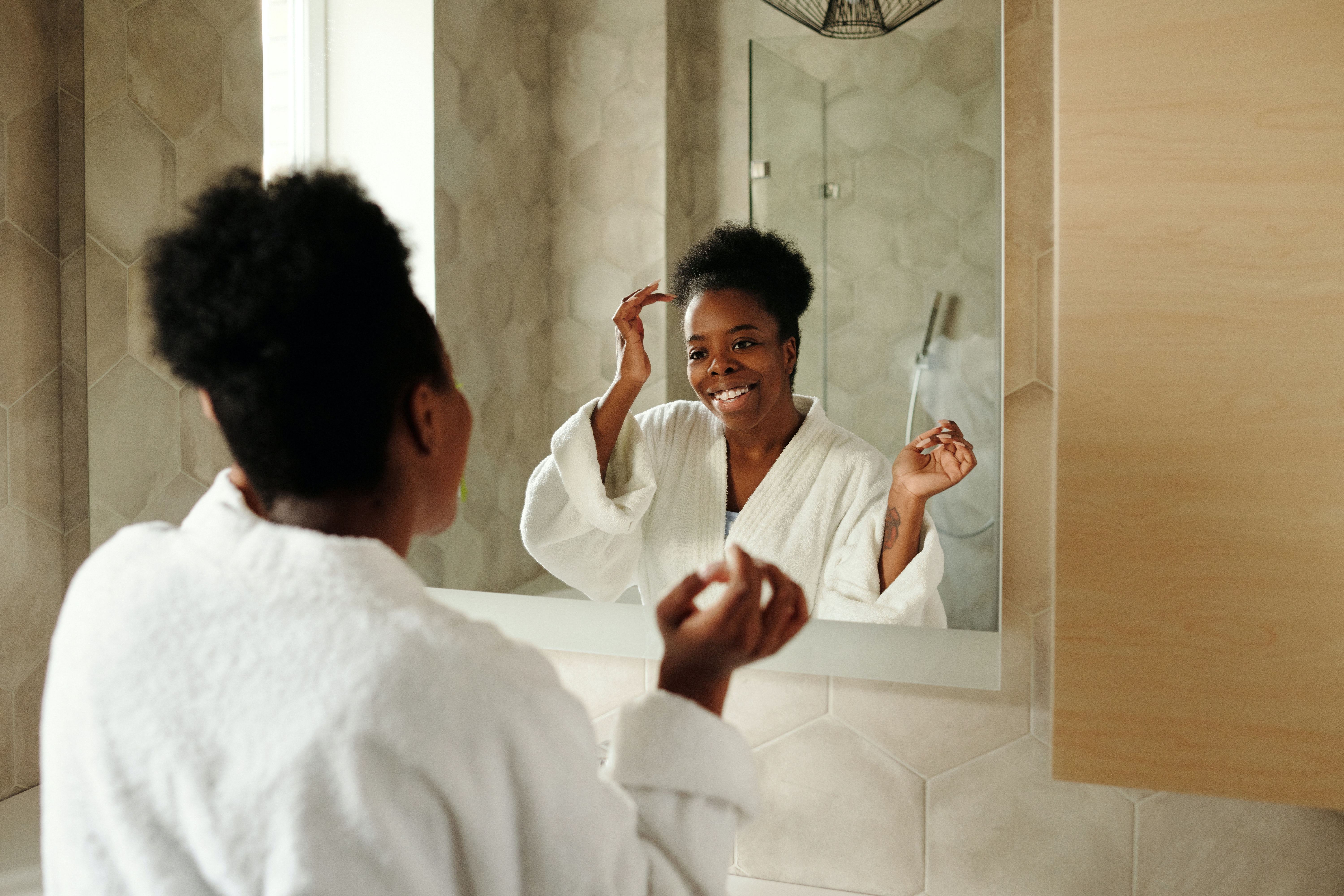 Woman with coily hair looking in the mirror