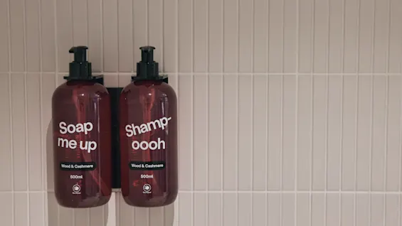 To veggmonterte dispensere merket 'Soap me up' og 'Shampoooh' med duften 'Wood & Cashmere', 500 ml, på Stopover Hotel Falkenberg.