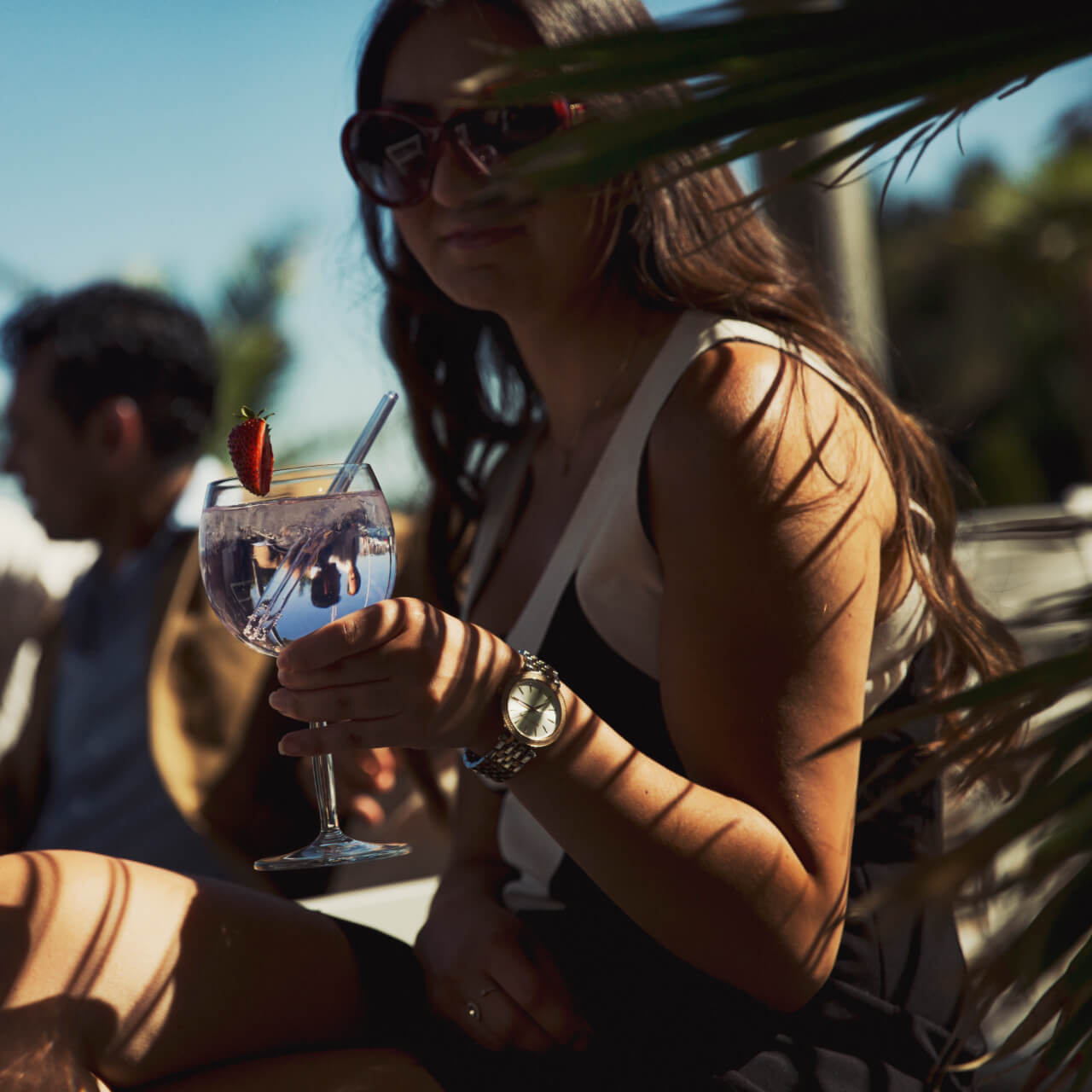 A girl with a drink outside in the sun at Strömstad Spa & Resort.