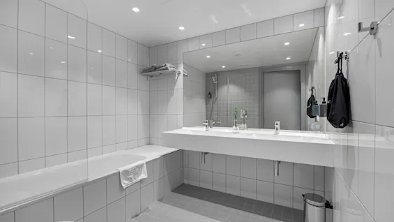 Et lyst, moderne bad på Comfort Hotel Porsgrunn med badekar, dobbel servant og stort speil. Rent og funksjonelt.