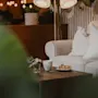 A warm and inviting lounge area with a sofa, a coffee table featuring tea, a slice of cake, and a small bouquet.