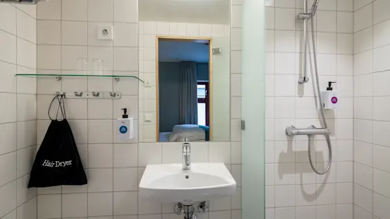 Badrum på Quality Hotel Tønsberg, rumstypen Compact Dubbel. Ett modernt badrum med handfat, spegel, dusch och en Hair Dryer påse.
