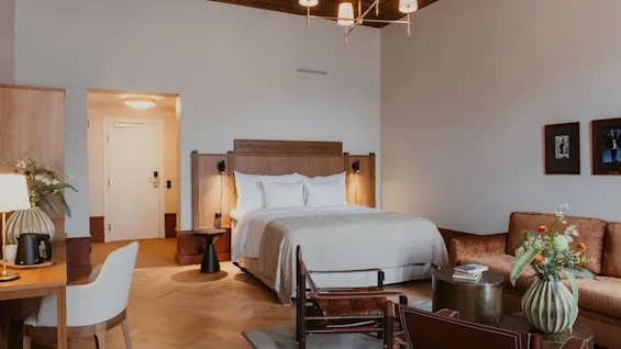 Home Hotel Baltzar - Junior Suite. A cozy and elegantly furnished hotel room with a large bed, a comfortable sofa, and a work desk.