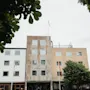 A multi-story building with the text SLOTTS PARKEN on its facade, framed by green trees under a cloudy sky.
