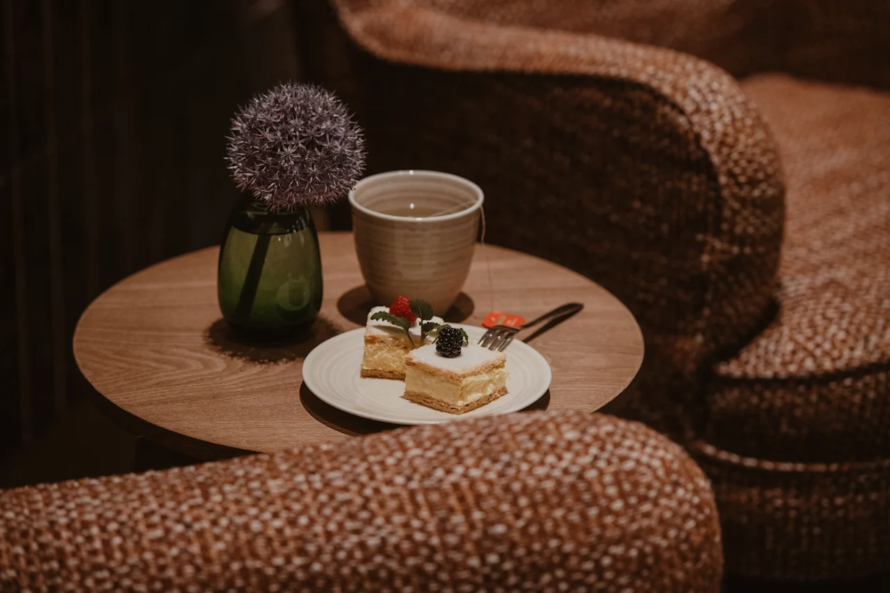 A delightful moment with cake and a hot beverage on a small table, surrounded by plush seating.
