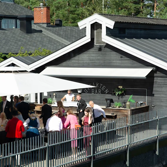 Utendørs arrangement på terrassen ved "Utsikten Bar" med gjester i festantrekk og bunader.