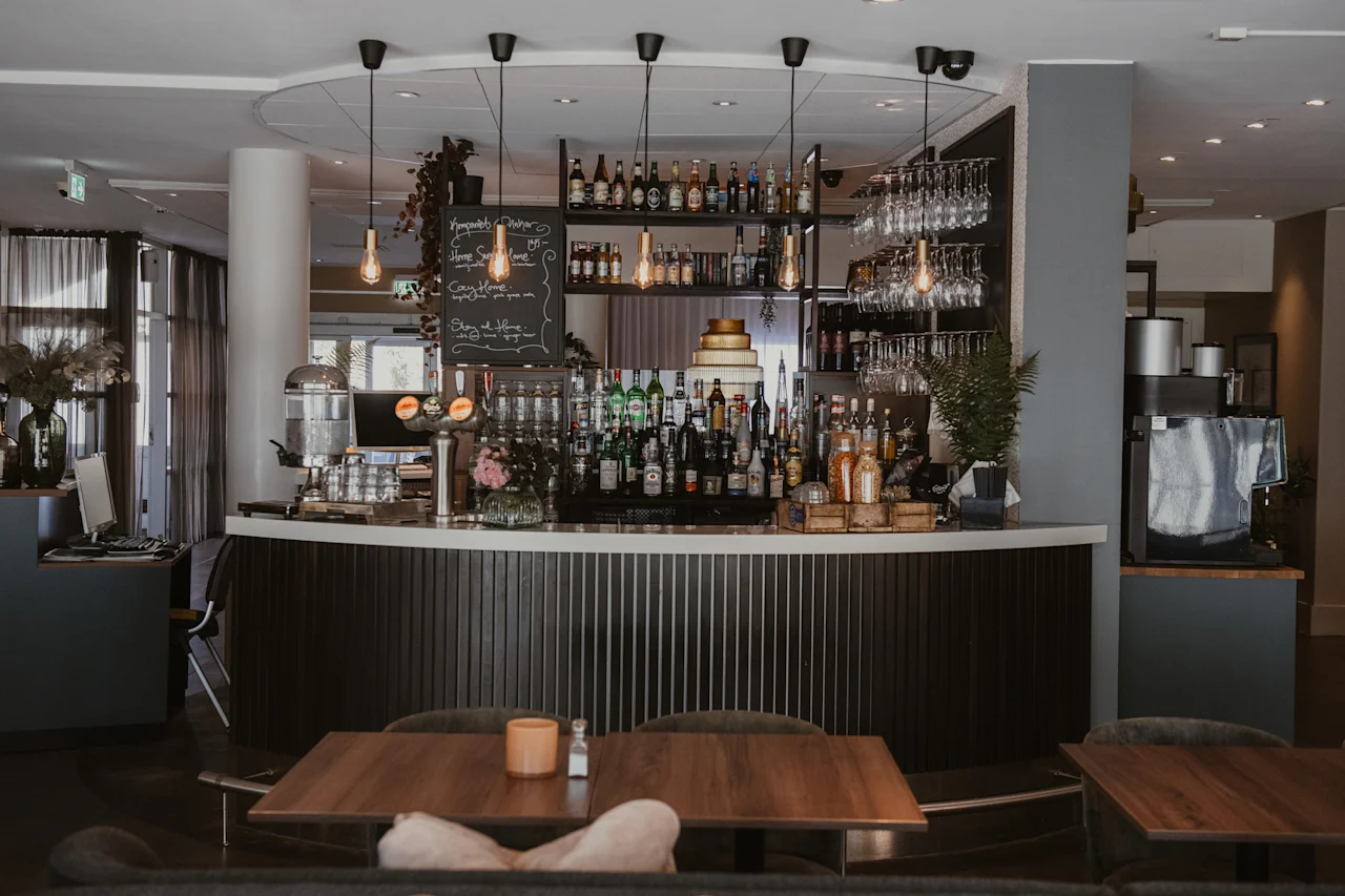 En hotellbar med en välfylld disk, hängande glas och en skylt: Komplett bar, Home Sweet Home, Cozy Home, Stay at Home.