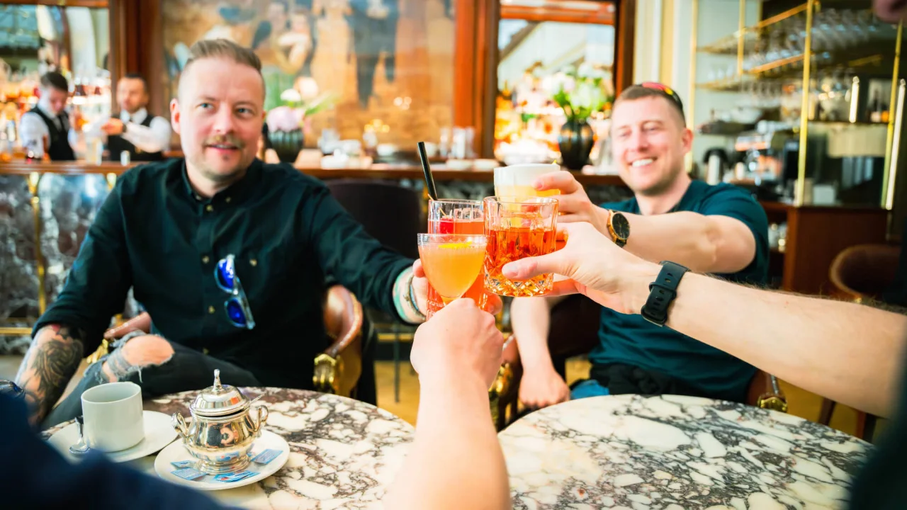 Vänner skålar med färgglada drinkar på Kämp Bar i Helsingfors.