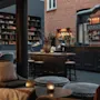 En hyggelig hotellounge med bar, komfortable siddepladser og hylder. En tavle siger Enjoy og en menu viser forskellige drinks.