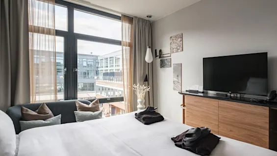 A modern hotel room at Farris Bad in Larvik with a large window, comfortable bed, and a TV for relaxation.