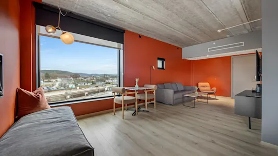 Et moderne og innbydende hotellrom på Comfort Hotel Porsgrunn med stort vindu, byutsikt, koselig sittegruppe og spiseplass.