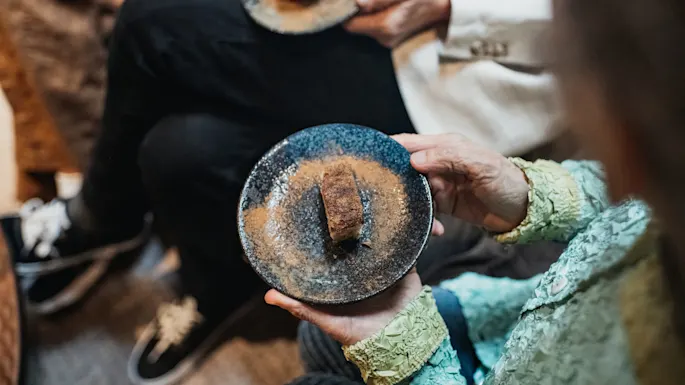 People sharing dessert on ceramic plates, close-up, indoors, indicating a social or communal gathering.