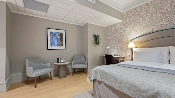 A cozy hotel room with a comfortable bed, a functional desk, and a relaxing seating area for guests.