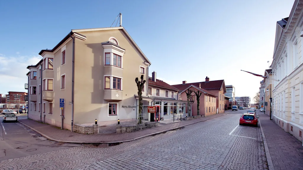 Et gatehjørne med bygninger, en merket "HOTEL MADOREN" og "Carino E CaffeBaren."