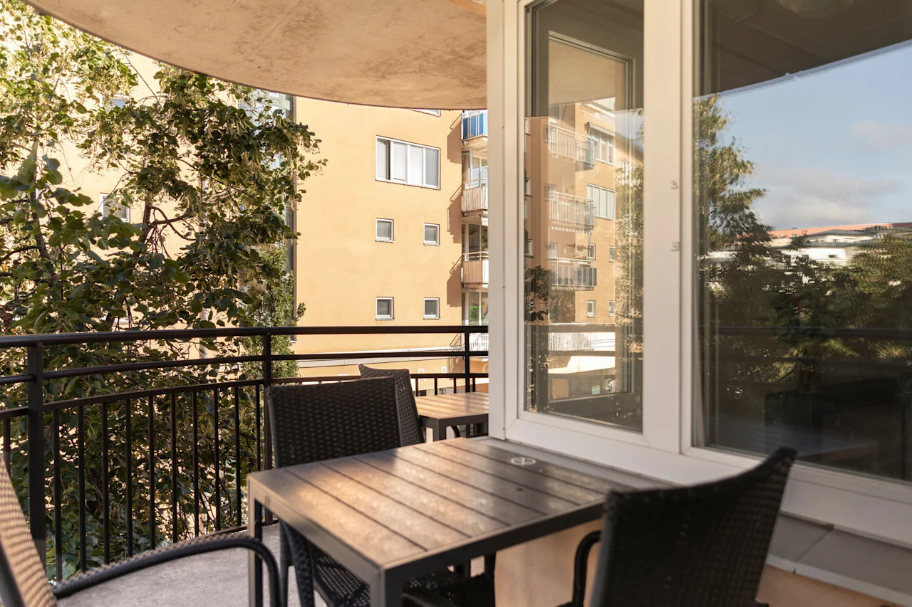 Balkong på Home Hotel Tapto med utemöbler, med utsikt över en byggnad och träd en solig dag.